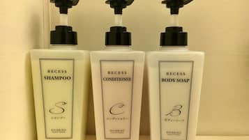 Three bottles of Shiseido products: shampoo, conditioner, and body soap, arranged on a shelf.