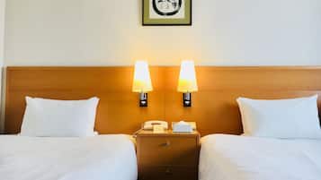 A hotel room with two beds, a nightstand with a telephone and tissues, and wall-mounted lamps.