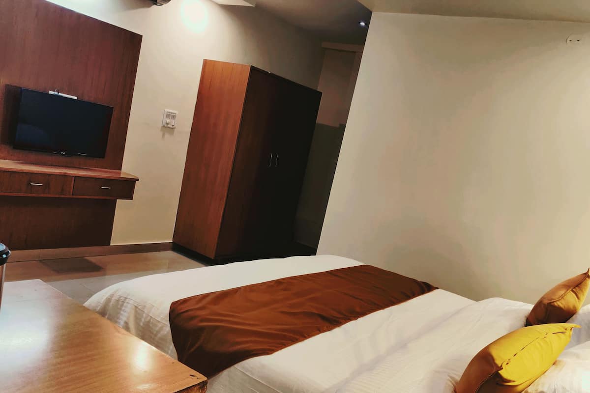 A hotel room with two beds, a TV on the wall, and a wooden table.