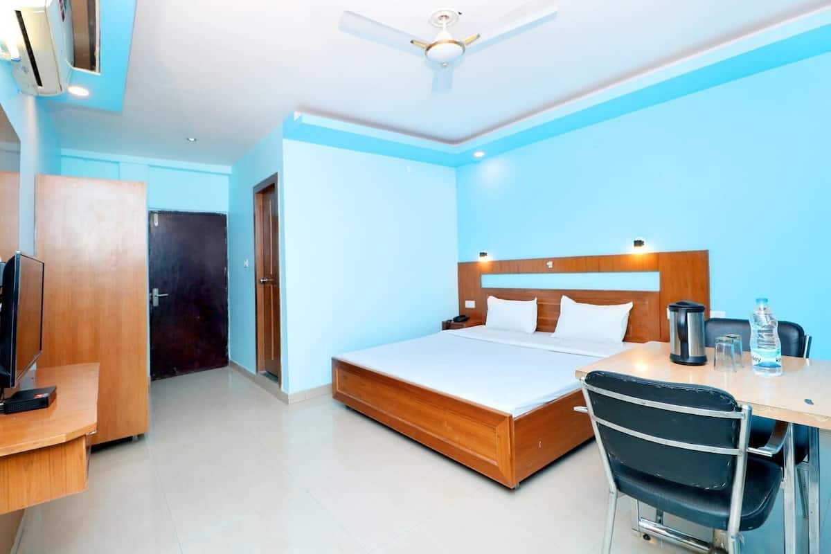 A hotel room with a bed, desk, chair, and a ceiling fan.