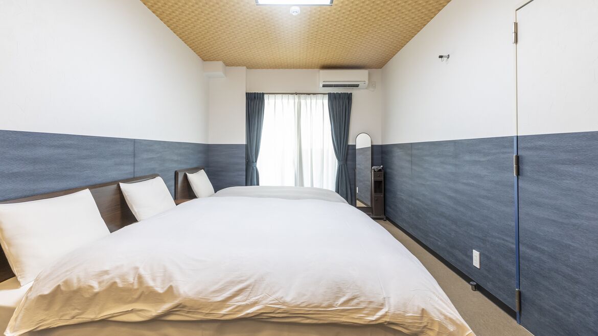 Quarto de hotel com uma cama grande, um espelho e uma janela com cortinas.