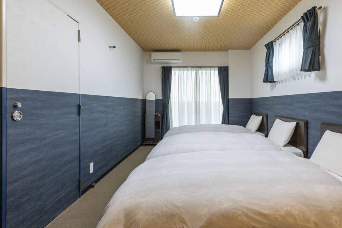 Et hotelværelse med en stor seng, et garderobeskab, et spejl og et vindue med gardiner.