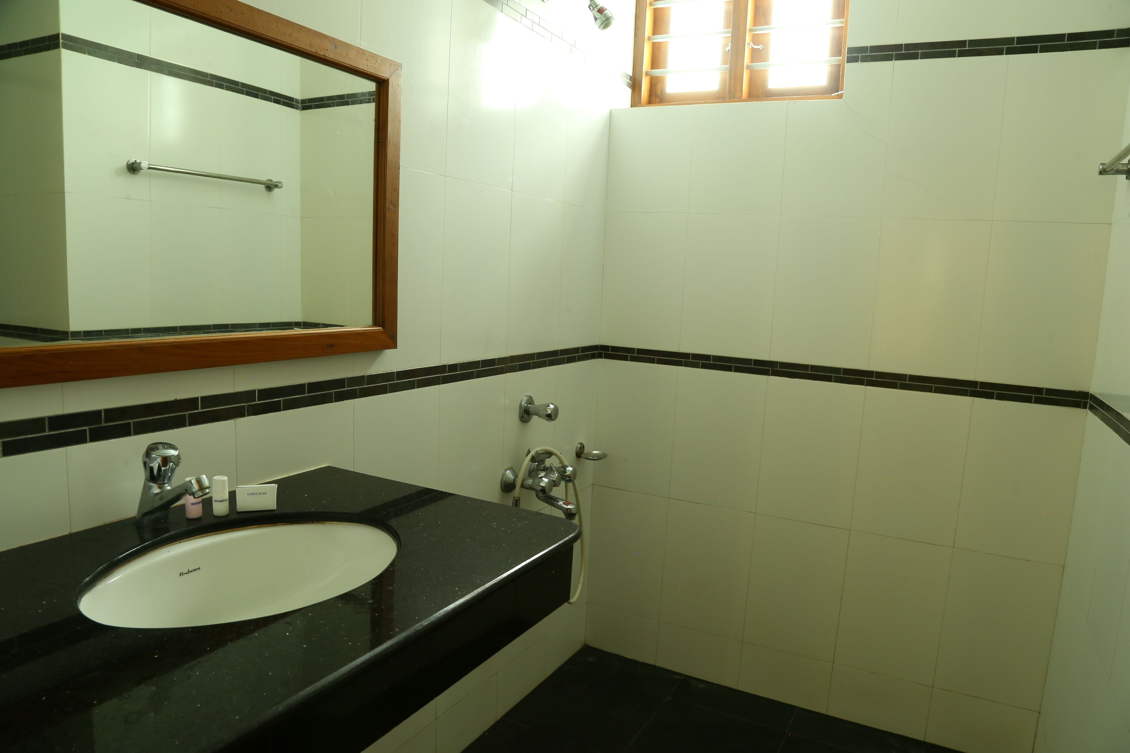 A bathroom with a black countertop sink, a mirror, and a shower area.
