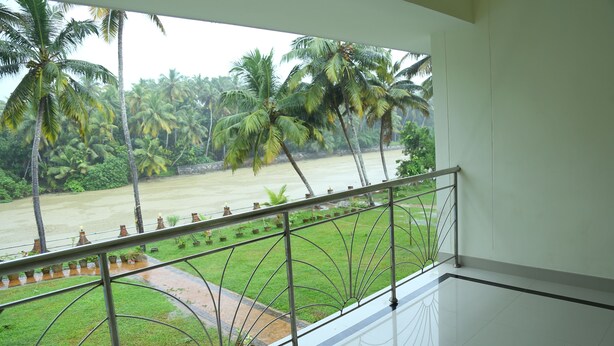 A balcony with a metal railing overlooking a river and palm trees. - Travancore Island Resort (Thiruvananthapuram)
