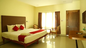 A hotel room with a large bed, two chairs, a small table, and a door. - Travancore Island Resort (Thiruvananthapuram)