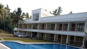 A modern hotel with a swimming pool, multiple balconies, and a parking area. - Travancore Island Resort (Thiruvananthapuram)