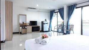 A hotel room with a bed, a TV, a minibar, a desk, and a balcony with a chair. - Rinn Boutique House (Chiang Mai)