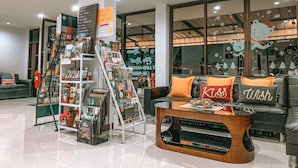 A modern interior with a display of travel magazines, a coffee table, and a couch with decorative pillows. - Rinn Boutique House (Chiang Mai)
