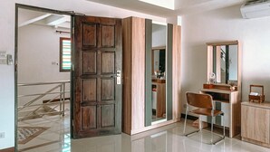A modern bathroom with a wooden door, a mirror, and a vanity with a chair. - Rinn Boutique House (Chiang Mai)