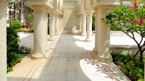 Un couloir bordé de colonnes et d’arches, qui mène à une verrière.