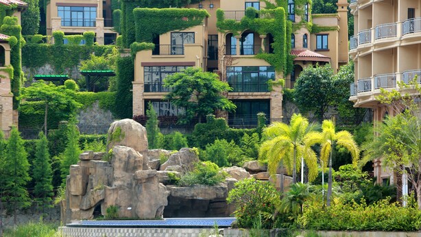 Un quartier résidentiel composé d’immeubles à plusieurs étages, agrémenté d’un jardin rocheux et bordé d’un plan d’eau.
