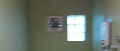 A small bathroom with a toilet, a window, and a wall-mounted heater.