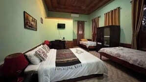 Una stanza con due letti, una televisione e un soffitto in legno.
