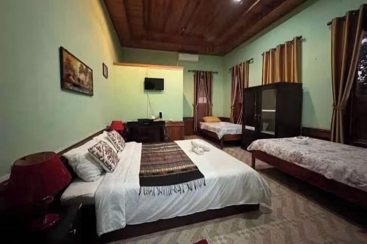 A room with two beds, a television, and a wooden ceiling.