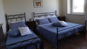 Ein Zimmer mit zwei Betten, jeweils mit Kopfteil und Fußteil, sowie einem kleinen Nachttisch mit Lampe.