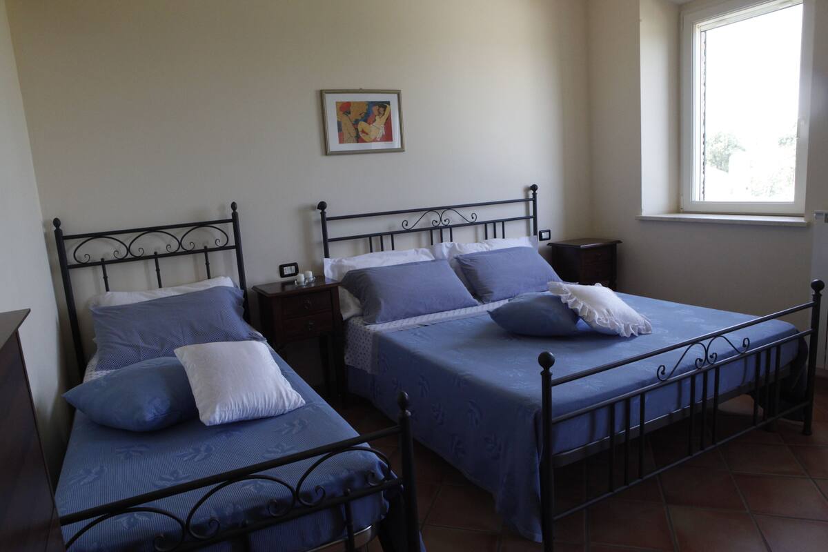 Een kamer met twee bedden, elk met hoofdeinde en voeteinde, en een klein nachtkastje met een lamp.