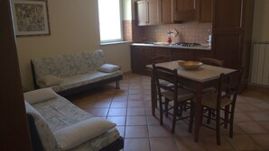 Eine kleine Küche mit Esstisch, Holzschränken und einer Couch.