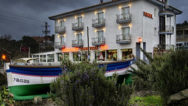 Een gebouw met een restaurant genaamd 'Bona Vista Bar' en een boot afgemeerd voor de deur.