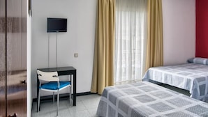 Een hotelkamer met een bureau, stoel, twee bedden, een televisie en gordijnen.