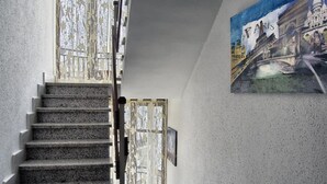 Een trap die leidt naar een kamer met een groot raam en een schilderij van Parijs aan de muur.