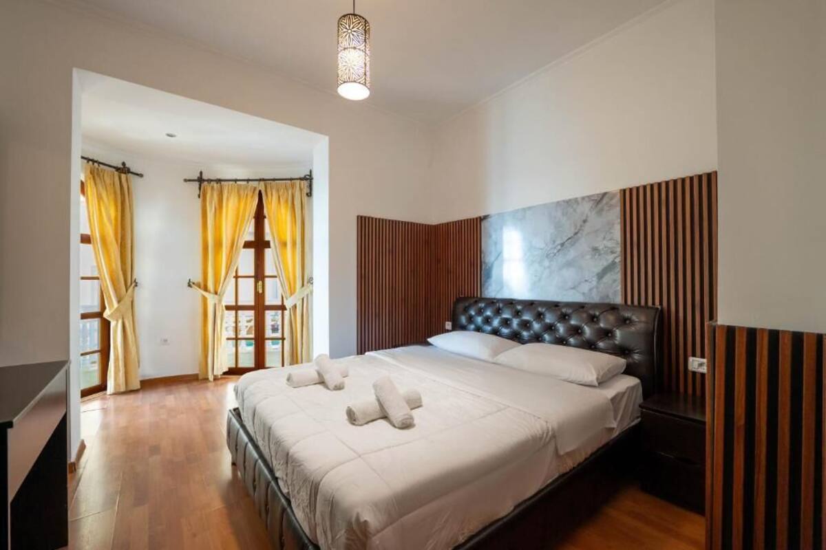 Un dormitorio con una cama grande, suelo de madera y vistas al exterior.