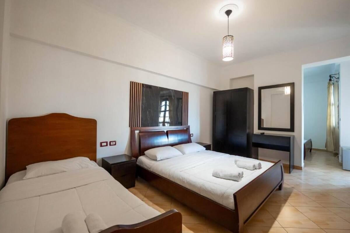 Habitación de hotel con dos camas, un escritorio, un armario y un espejo grande.