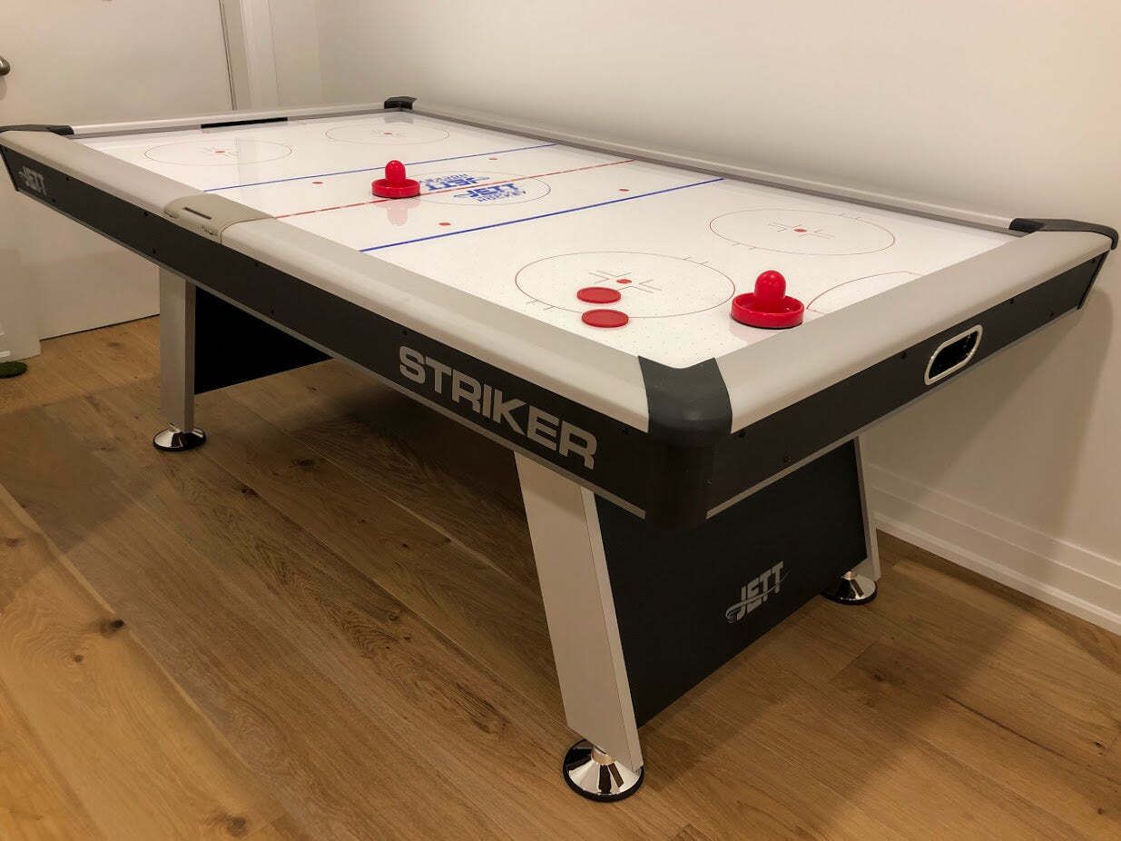 A table hockey game with a white and black table, red puck holders, and the brand name 'STAKER' visible.