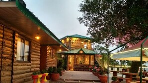 A log cabin with a porch, outdoor seating, and potted plants. - Jharipani Castle (Dehradun)