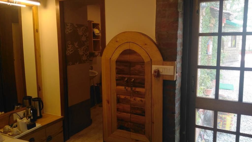 A room with a wooden door, a window with a view of the outside, and a counter with kitchen appliances.