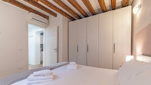 Un dormitorio con una cama grande, vigas de madera en el techo, un armario y un equipo de aire acondicionado.