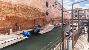 Un canal con barcos amarrados, un muro de ladrillo y un paseo de madera.