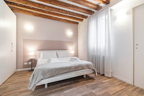 A bedroom with a bed, bedside lamps, a wooden ceiling, and a white door. - Ca' della Darsena - Arsenale by Wonderful Italy (Venice)