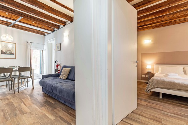 Una habitación moderna con techo de madera, un sofá, una cama y un área de comedor con sillas y una mesa.