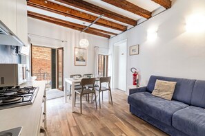 Eine moderne Küche mit Gasherd, Esstisch mit Stühlen, einem blauen Sofa und einer Holzzieldecke.