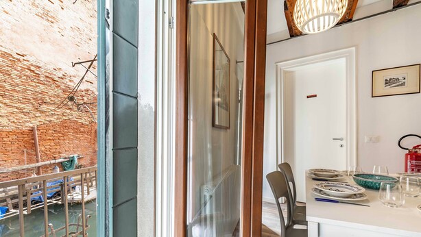 Un comedor con una mesa dispuesta para dos personas, un radiador y un extintor en la pared.
