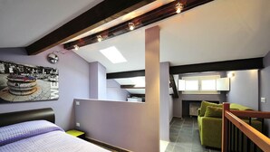 A bedroom with a bed, a green armchair, a small table, and a painting on the wall. - Palace La Vida Apartments by Wonderful Italy (Venice)