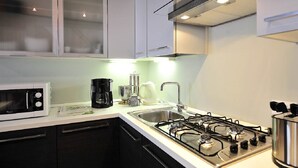 A modern kitchen with white cabinets, a gas stove, a microwave, and a coffee maker. - Palace La Vida Apartments by Wonderful Italy (Venice)