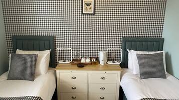 A hotel room with two beds, a nightstand, and a houndstooth-patterned wallpaper.
