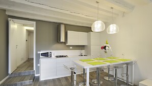 Una cocina moderna con armarios blancos, campana extractora de acero inoxidable y una barra con taburetes.
