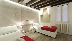 Un dormitorio moderno con una cama grande, un sofá más pequeño, una mesita de noche y una ventana con persianas.