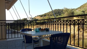 Un balcón con mesa y sillas, con vistas a un paisaje montañoso.
