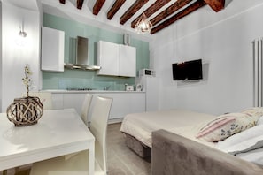 Un dormitorio compacto con cama, mesita de noche y pequeña área de kitchenette.