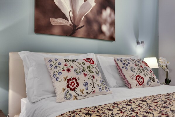 A bed with floral-patterned pillows and a large floral artwork on the wall. - Ca Furlan (Venice)