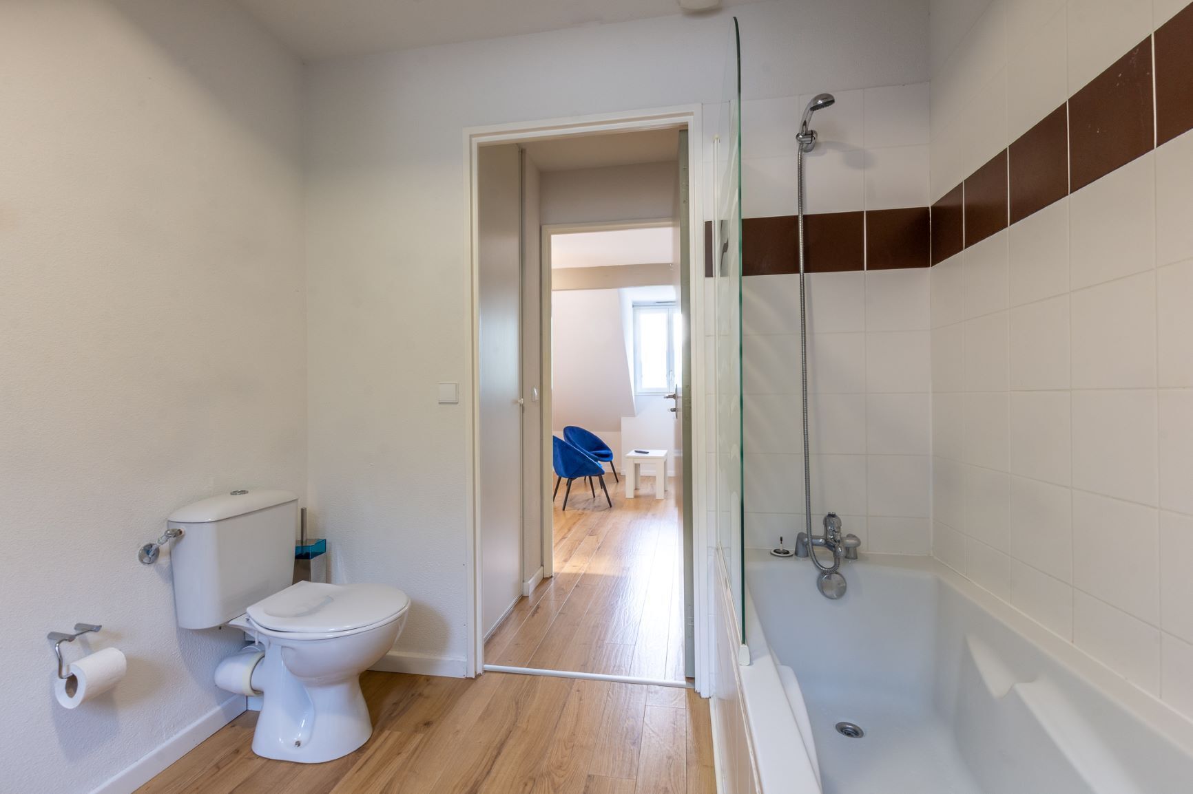 A modern bathroom with a toilet, shower, and glass door leading to a hallway.