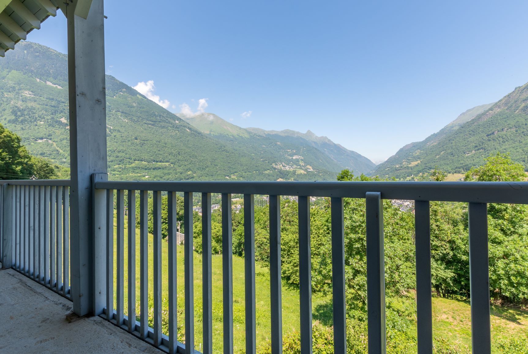 A balcony with a metal railing overlooking a mountainous landscape.