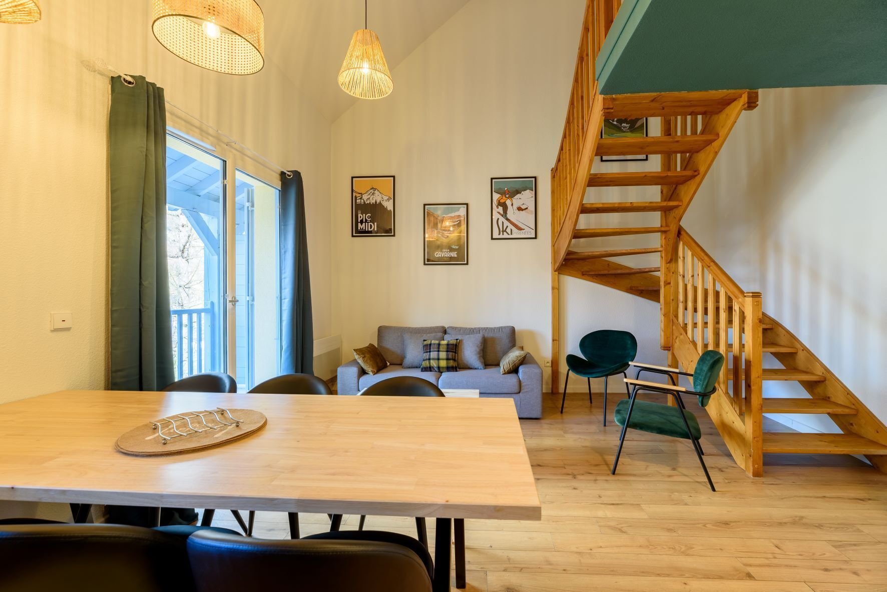 Una sala moderna con una escalera de madera, una mesa de comedor y un sofá.