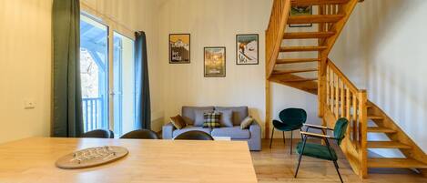 Una sala moderna con una escalera de madera, una mesa de comedor y un sofá.