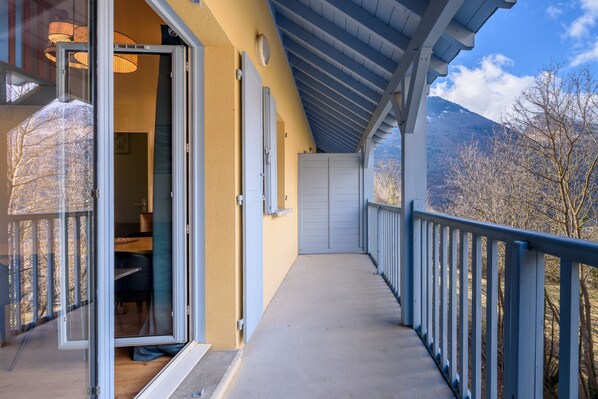 Un balcón con vistas a las montañas, una puerta corrediza de vidrio y piso de madera.