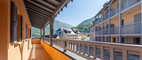 A balcony with a view of a mountain and a building with multiple balconies.