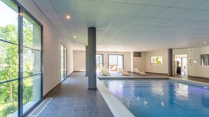 An indoor swimming pool with clear glass walls, a tiled floor, and a ceiling with recessed lighting. - Résidence Les Balcons de l'Yse (Luz-Saint-Sauveur)